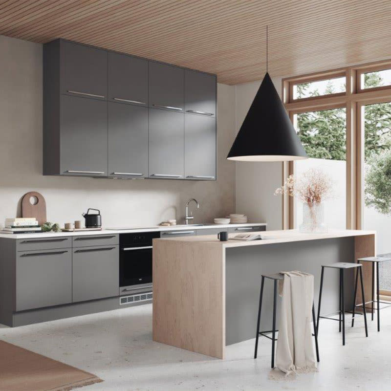 Moderne grå kjøkken med lyst trebord, svart pendellampe og store vinduer.