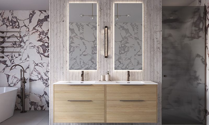 Lyst baderom med dobbel treskapvask, bakbelyste speil, marmormønstrede vegger og frittstående badekar