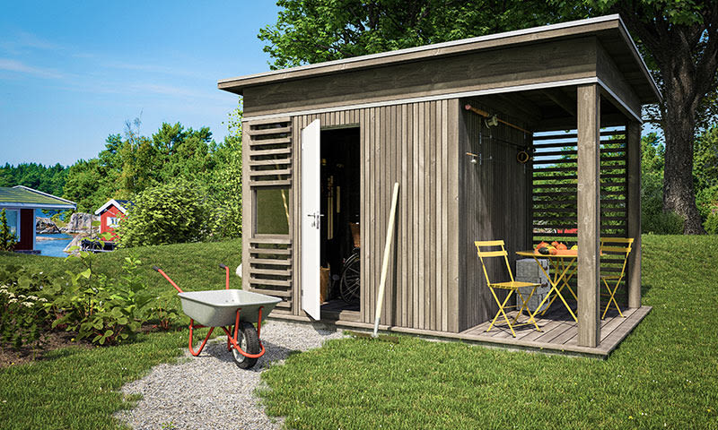 Grå hageskur med åpen hvit dør, gul uteplass, rød trillebår på grønt gress ved vann