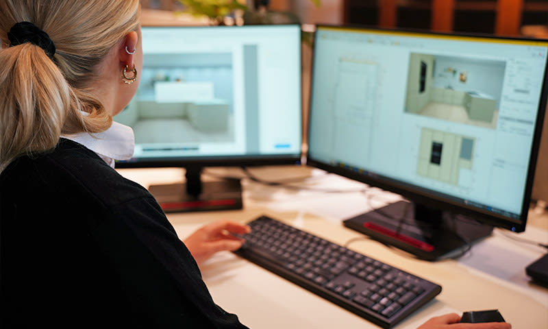 ansatt i byggmakker tegner opp kjøkken for kunde