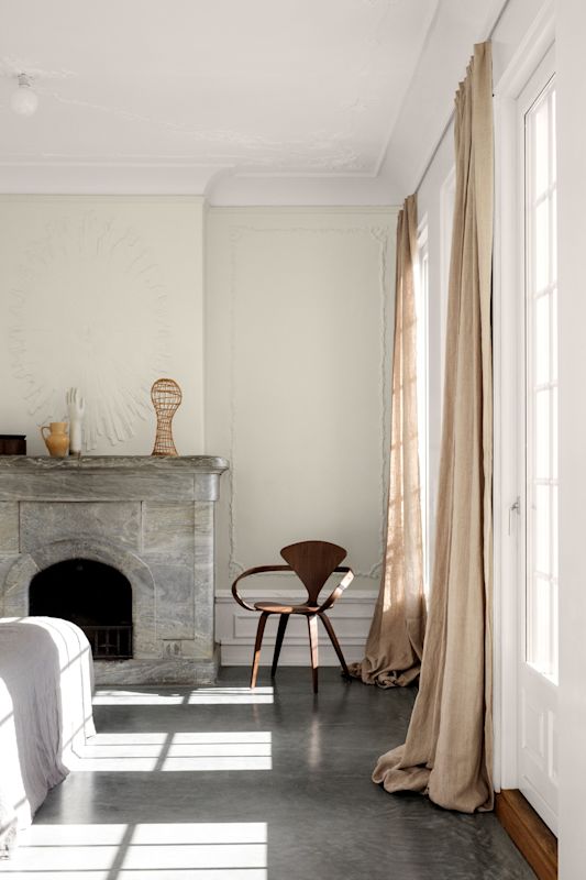 Solfylt rom med grå marmorpeis, beige gardiner og brun trestol.