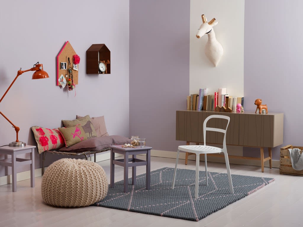 Lilla stue med sofa med puter, hvit stol, strikke-puff, bokhylle og hjortehode