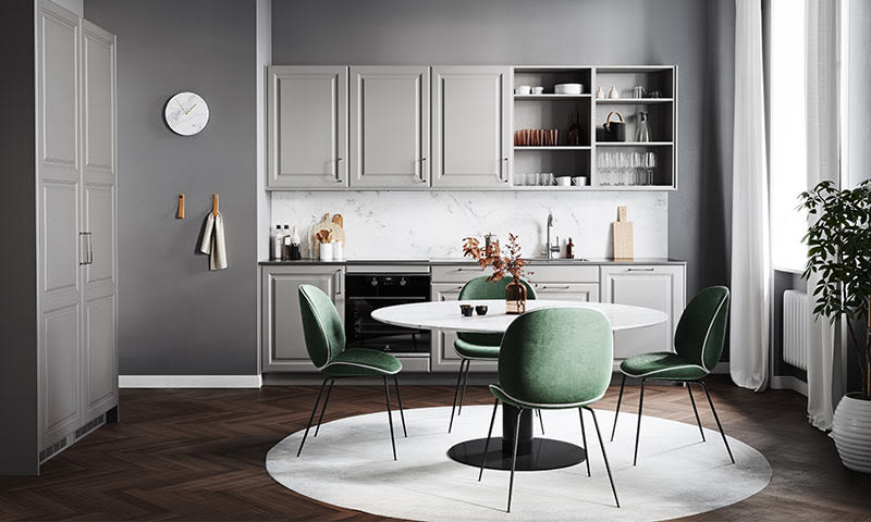 Moderne grått kjøkken med rund hvit marmorbord, fire grønne stoler, tregulv og dagslys fra vindu