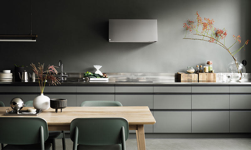 Moderne grått kjøkken med lys trebord, fire grønne stoler, vaser med rød bærkvist.