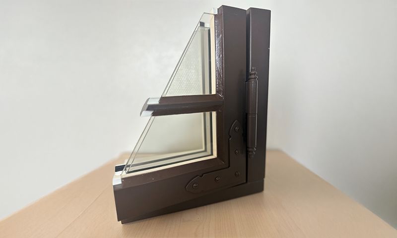 Brunt L-formet vindusprøvesnitt med to-lags glass på lyst trebord