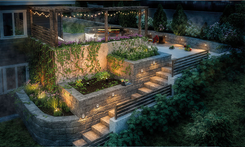 Aftenterrasse i flere nivåer med steinmurer, pergola med lyslenker, sitteplass og planter.