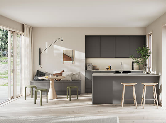 Lyst moderne kjøkken‐stue i beige og grått med kjøkkenøy, barkrakker og store vinduer.