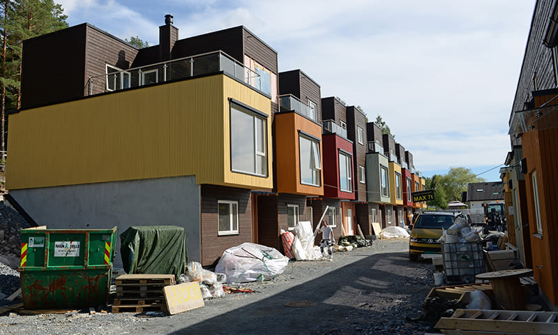 Rekke med fargerike rekkehus under bygging, gult, oransje, rødt og grønt, byggeplass