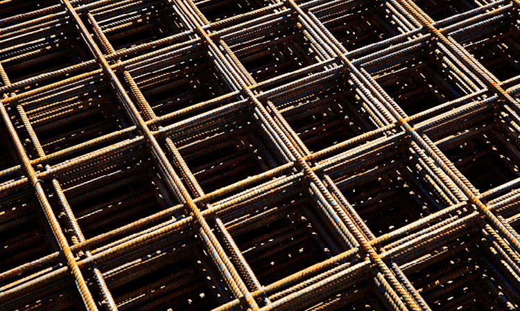 Rustent armeringsnett i stål, sollysspill over firkantet rutenett på byggeplass