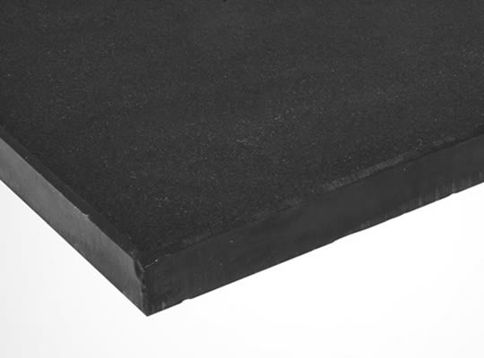 Nærbilde av hjørne på svart gummiplate med grov overflate mot hvit bakgrunn.