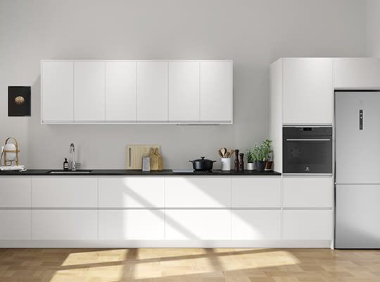Minimalistisk, hvitt kjøkken med sort benkeplate, integrert ovn og kjøleskap, sollys på tregulv.