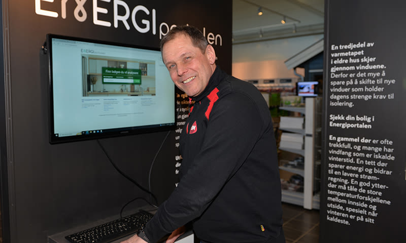 Person i svart jakke med røde detaljer foran skjerm som viser Energiportalens nettside på stand.
