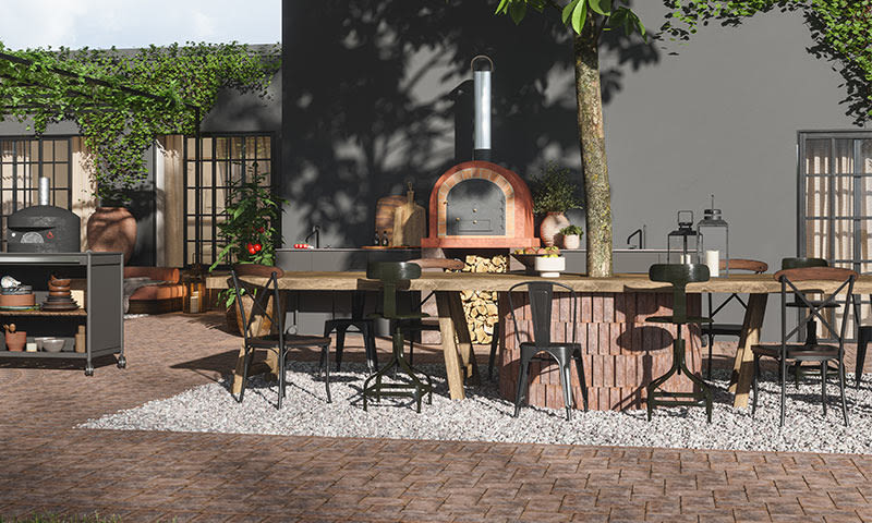 Uteplass med lang trefjøl, blandede stoler rundt rødbrun pizzaovn, hvit singel og grå vegg