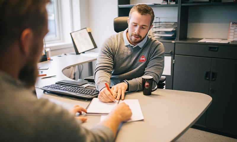 ansatt i byggmakker med papirarbeid for byggesøknad