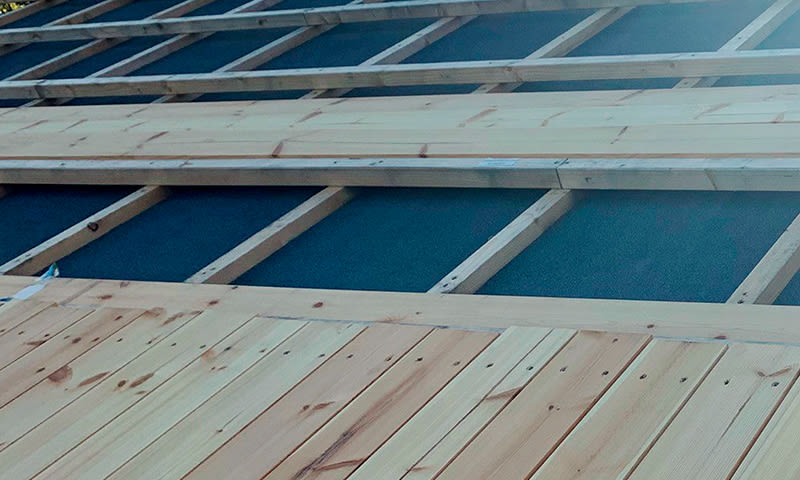 Uferdig tredekke med lyse planker på svart undertak og synlige bjelker