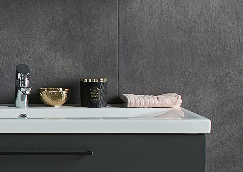 Hvit servant på svart underskap mot grå fliser, kromkran, gullskål, svart duftlys og rosa håndkle.