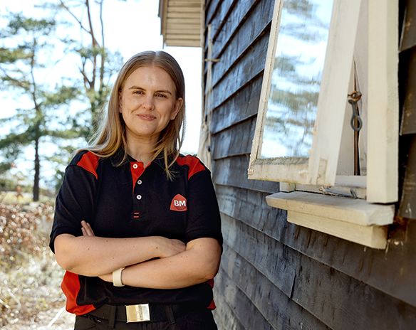 Jente utendørs med armene i kryss ved siden av hus