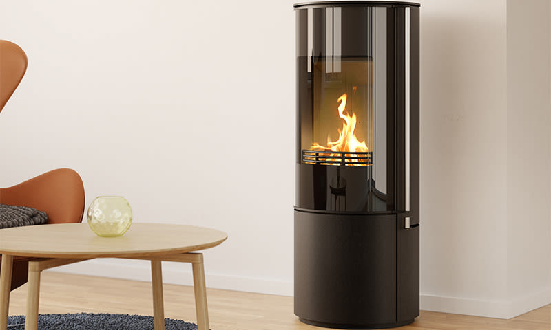 Moderne svart, rund peisovn med flammer i lys minimalistisk stue med trebord og oransje stol