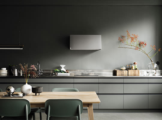 Minimalistisk kjøkken med grågrønne skap, stålbenk, trebord med grønne stoler, vase med blomster