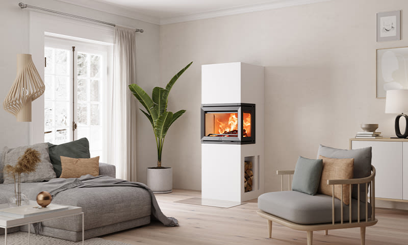 Moderne nordisk stue: hvit peis med ild, grå sofa, beige puter og grønn plante