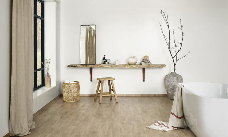 Lyst, minimalistisk baderom med hvitt badekar, flytende trehylle, speil og kvister