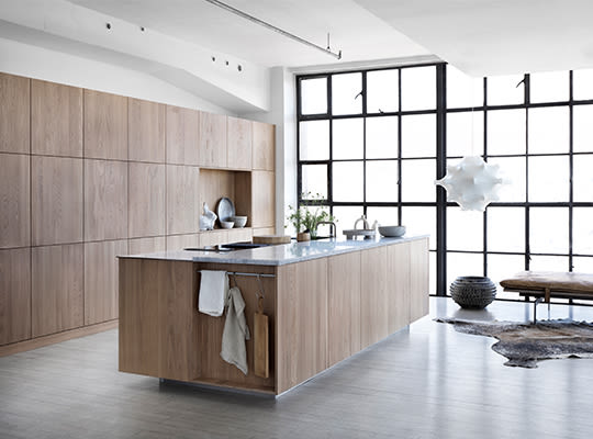 Moderne kjøkken med lyst tre, grå benkeplate, svart vindusvegg og minimalistiske detaljer.