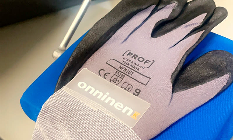 Grå/svarte arbeidshansker med “PROF Workwear” og “onninen”-etikett på blå overflate