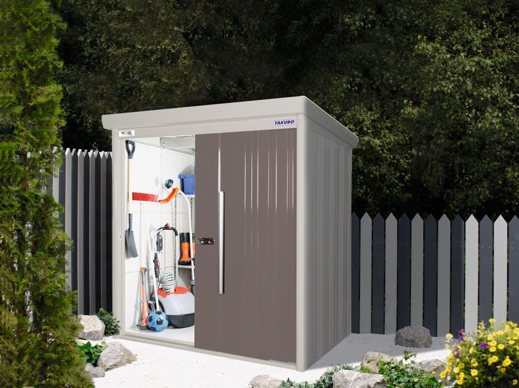 Grått og brunt hageskjul med åpen dør, synlige redskaper, gressklipper, blå ball og hvitt gjerde.