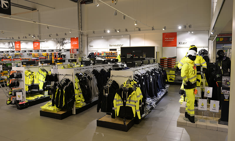 Butikkavdeling med gule refleksklær og verneutstyr på stativer og mannequiner.