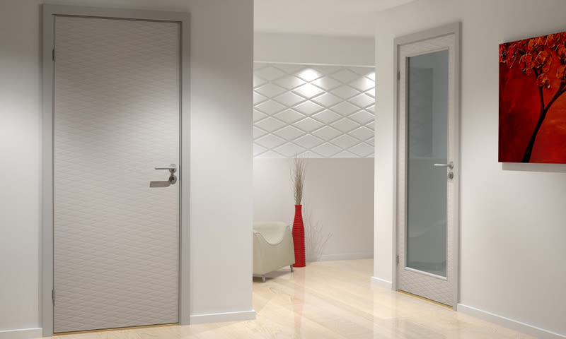 Hvit gang med to lyse dører (én glass), beige stol, høy rød vase og rødt maleri.