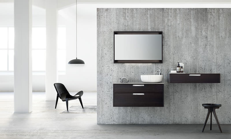 Moderne baderom med vegghengt mørkt treskap, hvit bollevask, rektangulært speil og svart stol