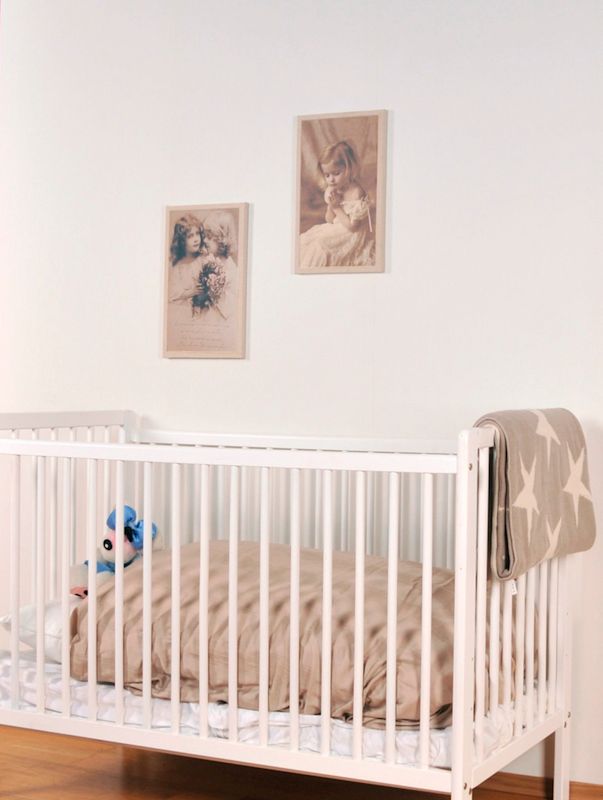 Hvit sprinkelseng med beige dyne, grått stjernepledd over siden og blå kosebamse under sepia bilder