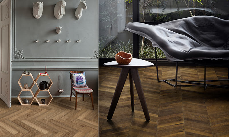 Grå vegg med hvite dyrehoder, bikubehylle, trekantbord med skål, svart lenestol ved vindu