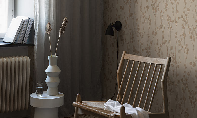 Lys stuekrok med trestol, hvit vase med pampasgress, dempet tapet og gardin.