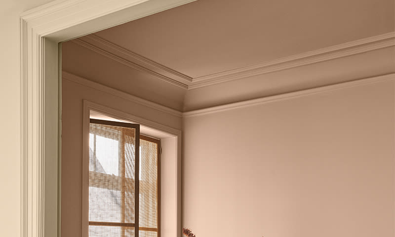 Tomt rom med beige vegger, hvit døråpning og vindu med lys, gjennomsiktig gardin.