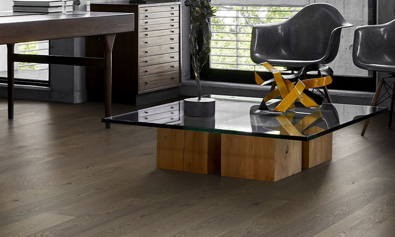 Moderne interiør med lavt glassbord på trekuber, gul abstrakt skulptur og to grå stoler