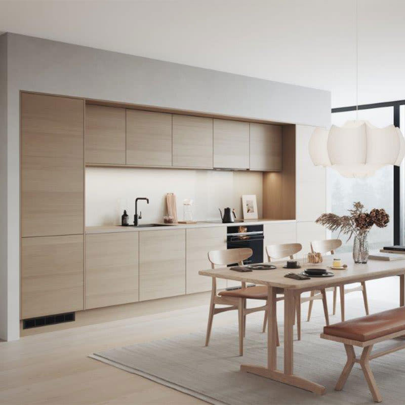 Moderne lyst kjøkken i lyse tresoner med spisebord, stoler, benk, hvit pendellampe og vase.