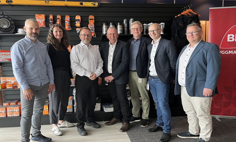 syv mennesker som står foran en vegg med produkter