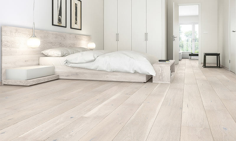 Lyst minimalistisk soverom med hvit dobbeltseng, hengende lamper, lyst tre og garderobe.