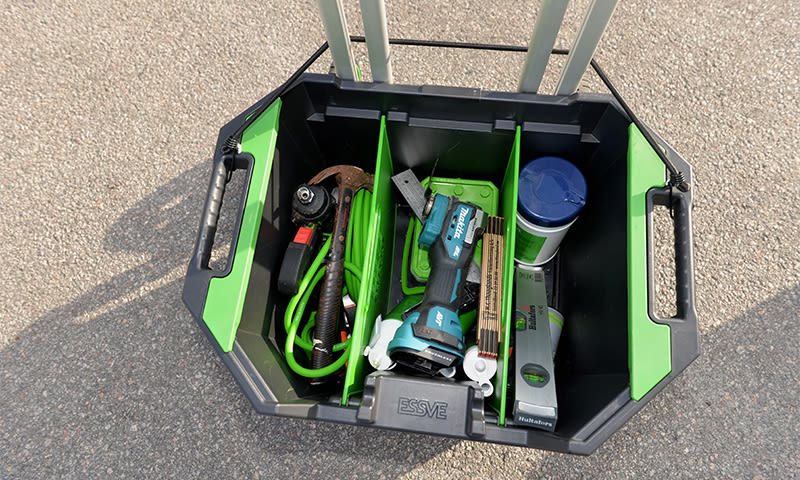 Svart/grønn verktøykasse på asfalt, delt med Makita-boremaskin, grønn kabeltrommel, vater og skruer