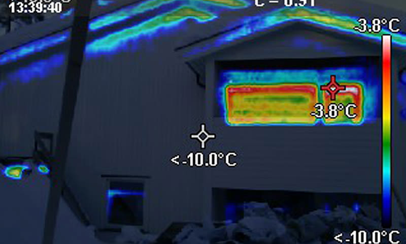 Termisk bilde av husfasade med kalde blå områder (-10 °C) og varmere vindu (rød-gul, -3,8 °C)