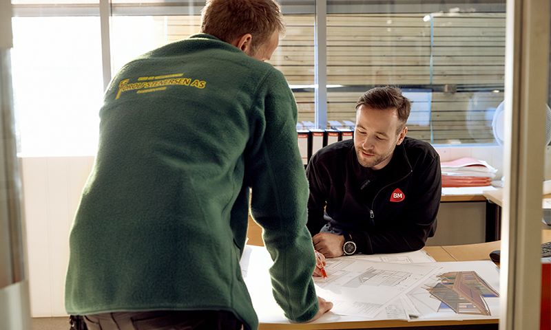 to menn som lener seg over et bord med papirer