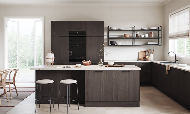 Lyst kjøkken med mørke trefronter, hvit kjøkkenøy med to hvite barkrakker og åpne hyller.