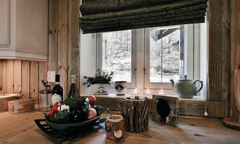 Rustikt kjøkkenbord med fargerike grønnsaker, vinflasker, tekanne, lys på snødekt vinduskarm