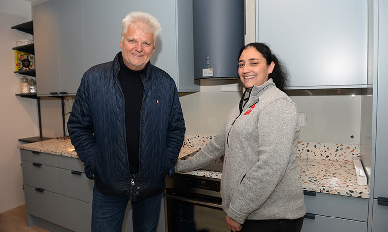 To personer i blå og grå jakke ved moderne kjøkken med grå skap og farget terrazzo benkeplate