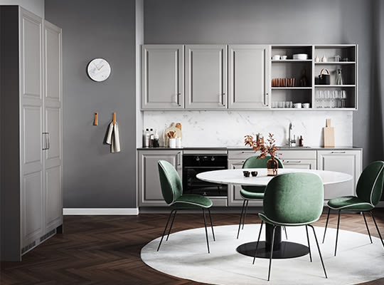 Moderne kjøkken med grå skap, hvit marmorbakvegg, rundt hvitt bord med fire grønne stoler.