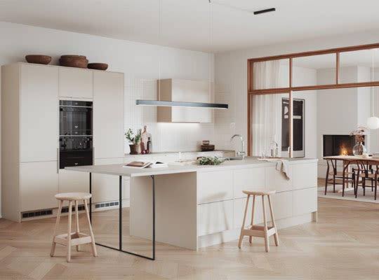 Lyse, moderne kjøkkenøy med hvite skap, lys parkett, to trekrakker og åpen spisestue.