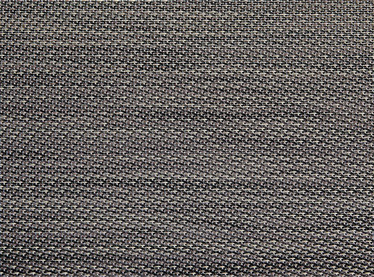 Nærbilde av gråsvart vevet tekstil med tett repeterende mønster.