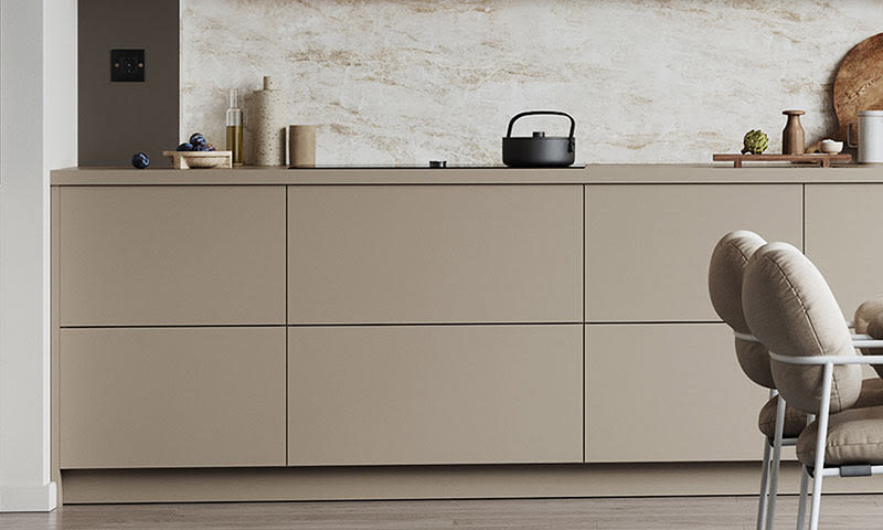 Minimalistisk lyst beige kjøkken med marmorflis, sort tekjele, grønne oliven og polstret stol