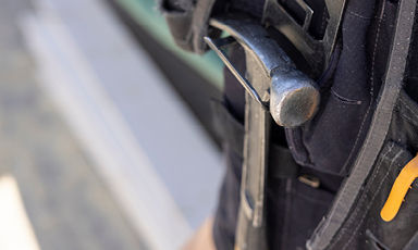 Nærbilde av mørk politivest med metallbatong og håndholdt radio.